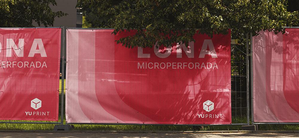 Lonas microperforadas YuPrint instaladas en vallas, ideales para obras y eventos con gran visibilidad.
